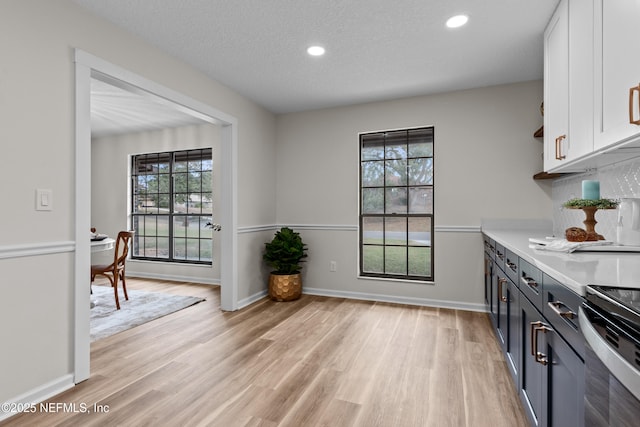 kitchen featuring a healthy amount of sunlight, a textured ceiling, light hardwood / wood-style flooring, and white cabinets