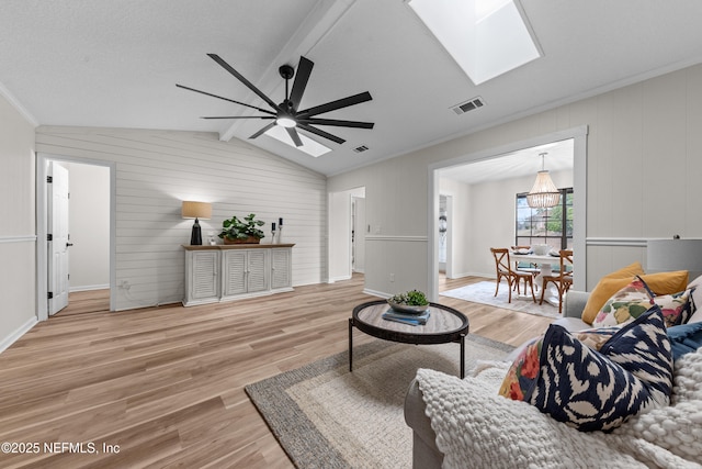 living room featuring hardwood / wood-style floors, crown molding, lofted ceiling with skylight, and ceiling fan