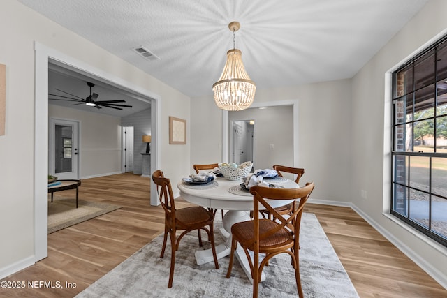 dining area featuring ceiling fan with notable chandelier, a textured ceiling, and light hardwood / wood-style floors