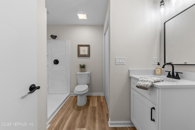 bathroom featuring vanity, hardwood / wood-style floors, walk in shower, and toilet