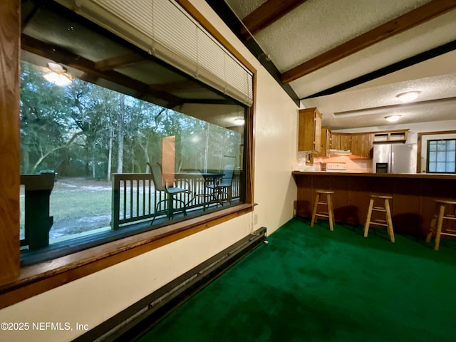 bar featuring stainless steel fridge with ice dispenser, lofted ceiling with beams, a textured ceiling, and dark colored carpet