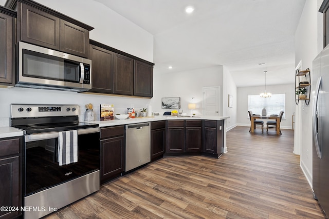 kitchen featuring dark brown cabinetry, decorative light fixtures, and appliances with stainless steel finishes