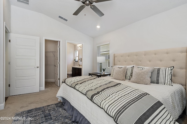 carpeted bedroom featuring vaulted ceiling, a walk in closet, ceiling fan, ensuite bath, and a closet