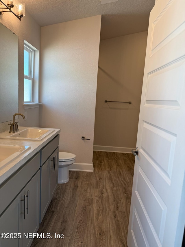8284 Helmsley Blvd, Jacksonville, FL 32219 - bathroom featuring wood finished floors, baseboards, a sink, a textured ceiling, and toilet