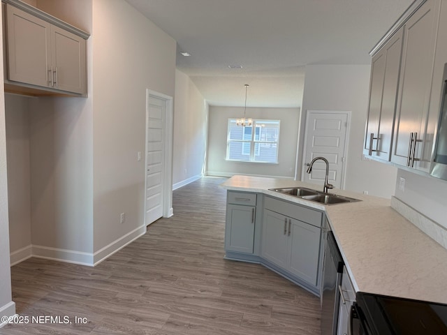 8284 Helmsley Blvd, Jacksonville, FL 32219 - kitchen featuring light wood-type flooring, gray cabinetry, a sink, a peninsula, and an inviting chandelier