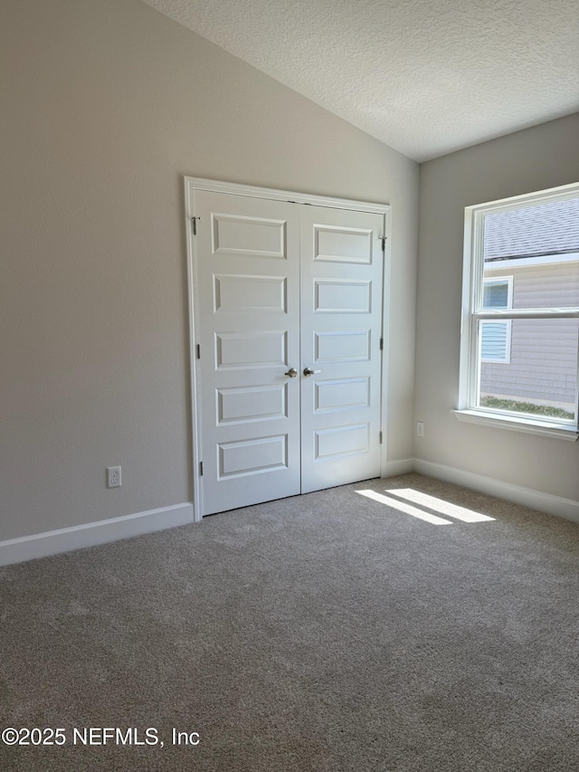 8284 Helmsley Blvd, Jacksonville, FL 32219 - unfurnished bedroom featuring a textured ceiling, a closet, carpet, baseboards, and vaulted ceiling