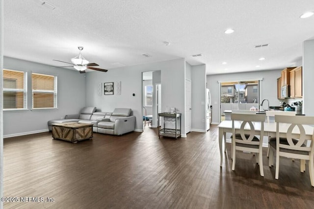 living room with dark wood-type flooring, ceiling fan, and a textured ceiling