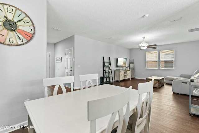 dining space with ceiling fan, a textured ceiling, and dark hardwood / wood-style flooring