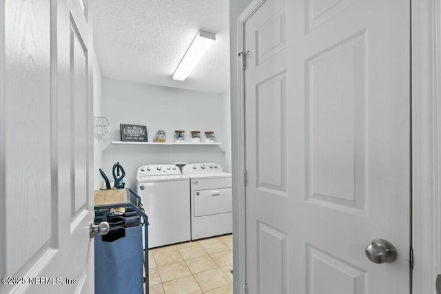 laundry room with light tile patterned flooring, separate washer and dryer, and a textured ceiling