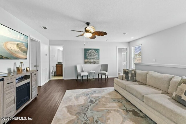 living room with a textured ceiling, dark hardwood / wood-style floors, and ceiling fan