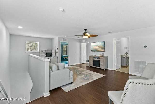 living room featuring dark wood-type flooring and ceiling fan