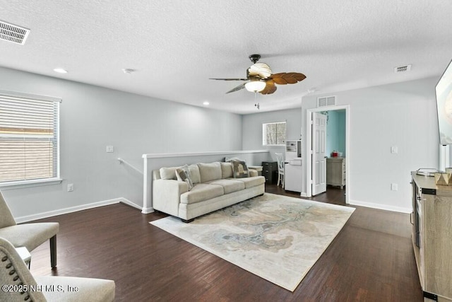 living room with ceiling fan, dark hardwood / wood-style flooring, and a textured ceiling