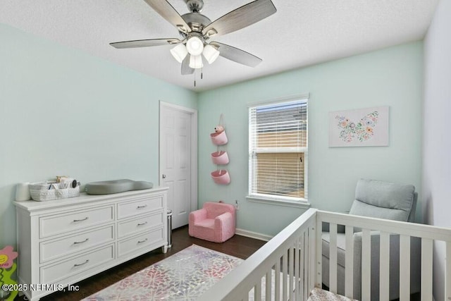 bedroom with ceiling fan, dark hardwood / wood-style flooring, and a crib