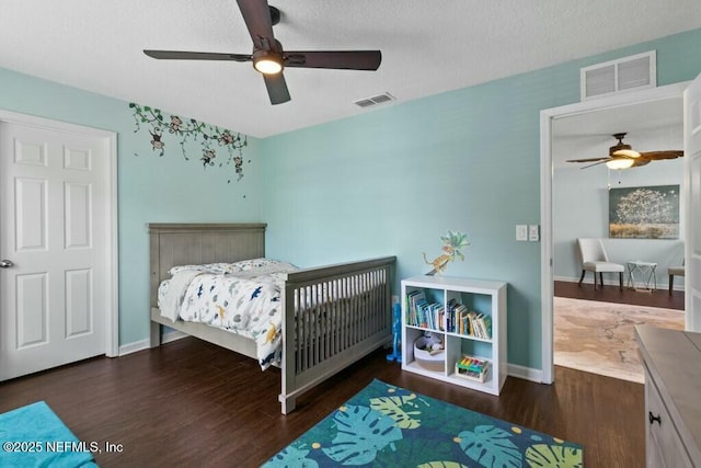 bedroom featuring a textured ceiling, dark wood-type flooring, and ceiling fan