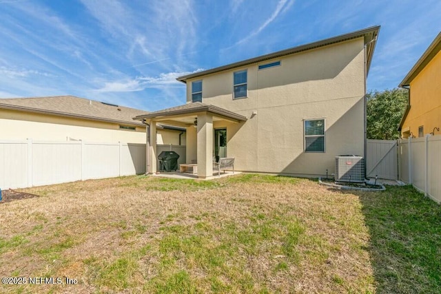 rear view of property featuring a yard, central AC unit, and a patio