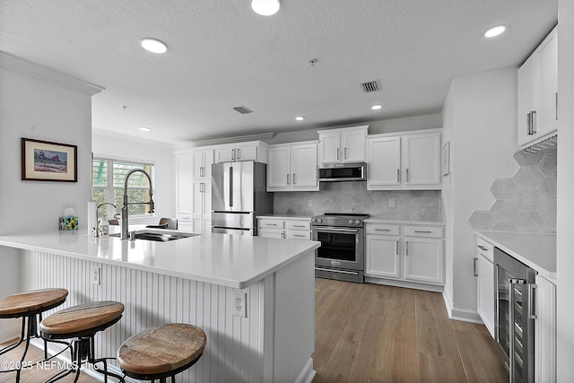 kitchen featuring white cabinetry, sink, a breakfast bar area, wine cooler, and stainless steel appliances