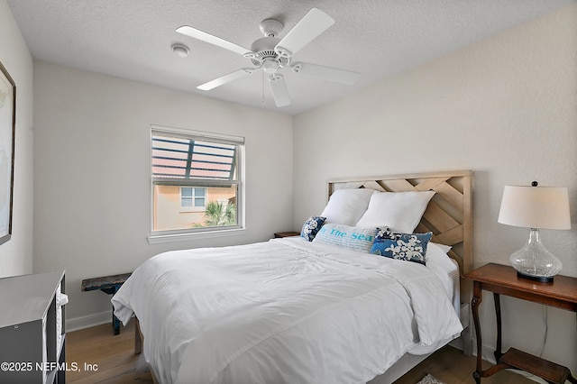 bedroom featuring ceiling fan, dark hardwood / wood-style floors, and a textured ceiling