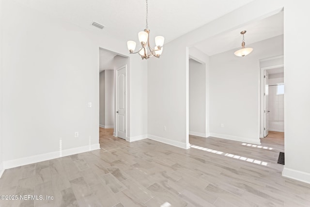 unfurnished room with a notable chandelier and light wood-type flooring