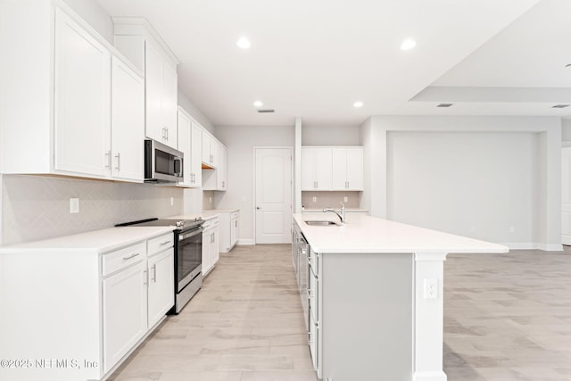 kitchen with white cabinetry, appliances with stainless steel finishes, and an island with sink