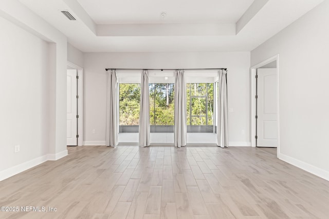 unfurnished room featuring light hardwood / wood-style floors and a tray ceiling