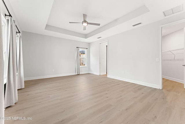 unfurnished bedroom featuring a raised ceiling, ceiling fan, and light wood-type flooring