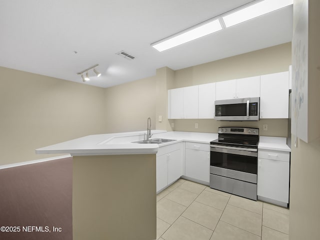 kitchen featuring stainless steel appliances, a peninsula, a sink, white cabinetry, and light countertops