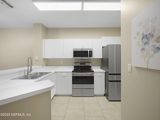 kitchen with appliances with stainless steel finishes, white cabinets, light countertops, and a sink