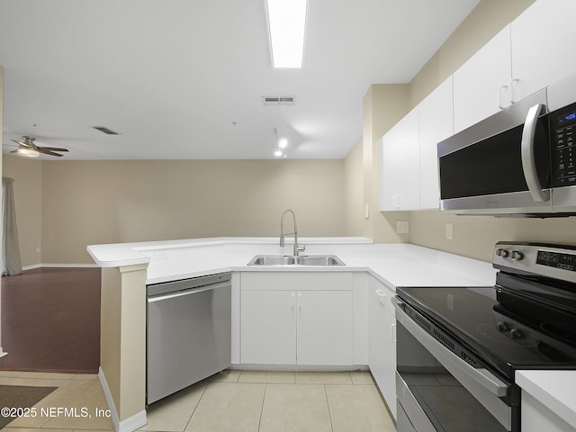 kitchen featuring light tile patterned floors, visible vents, a peninsula, stainless steel appliances, and a sink