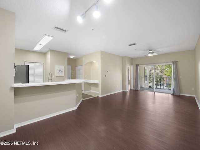 unfurnished living room with a sink, baseboards, visible vents, and wood finished floors