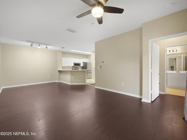 unfurnished living room featuring wood finished floors, a ceiling fan, visible vents, baseboards, and track lighting