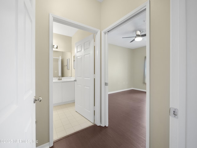 corridor with a sink, baseboards, and wood finished floors