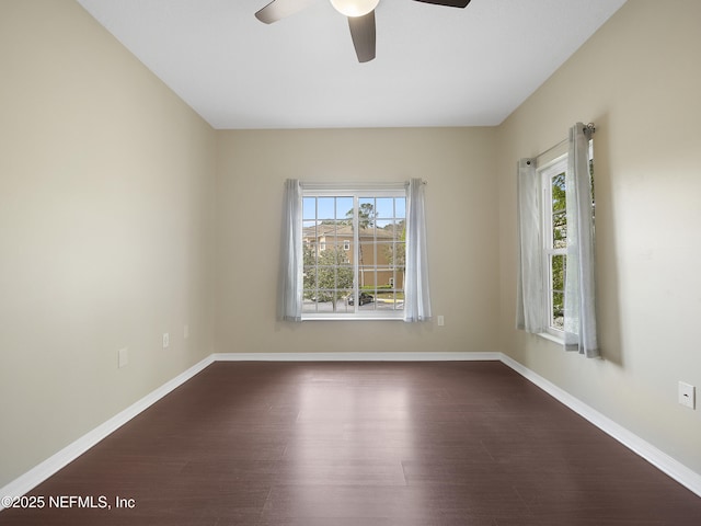 unfurnished room with dark wood-type flooring, a wealth of natural light, and baseboards