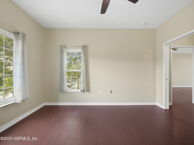 spare room featuring ceiling fan, baseboards, and dark wood finished floors