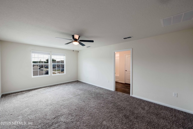 spare room with dark colored carpet, ceiling fan, and a textured ceiling