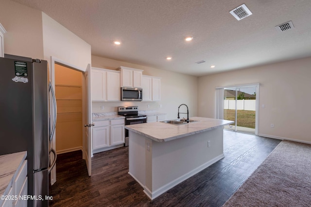 kitchen with appliances with stainless steel finishes, sink, white cabinets, a kitchen island with sink, and dark wood-type flooring