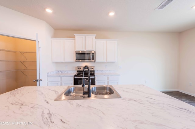 kitchen with white cabinetry, sink, light stone counters, and appliances with stainless steel finishes