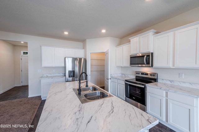 kitchen featuring white cabinetry, stainless steel appliances, sink, and a center island with sink