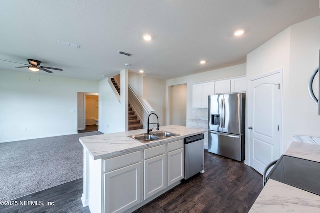 kitchen featuring appliances with stainless steel finishes, an island with sink, sink, white cabinets, and dark wood-type flooring