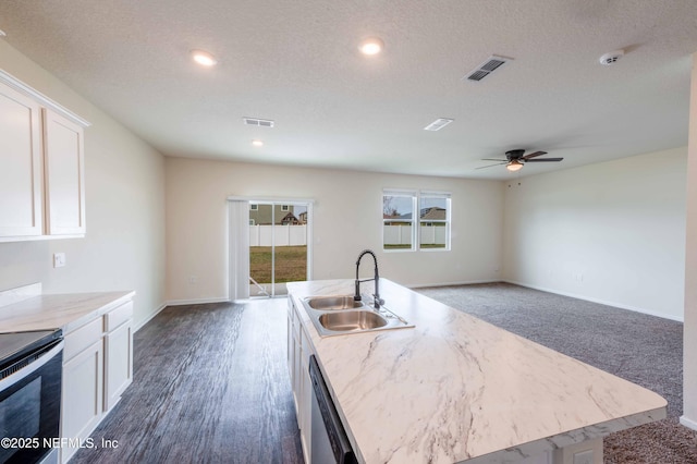 kitchen with sink, white cabinetry, stainless steel appliances, a textured ceiling, and a center island with sink