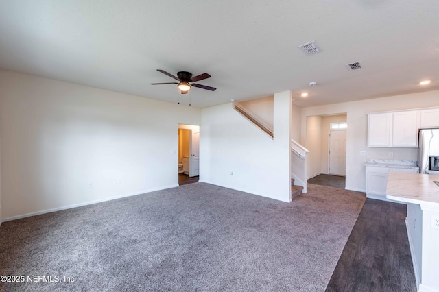 unfurnished living room with ceiling fan and dark colored carpet