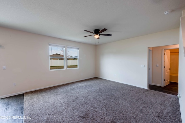 spare room featuring dark carpet, a textured ceiling, and ceiling fan