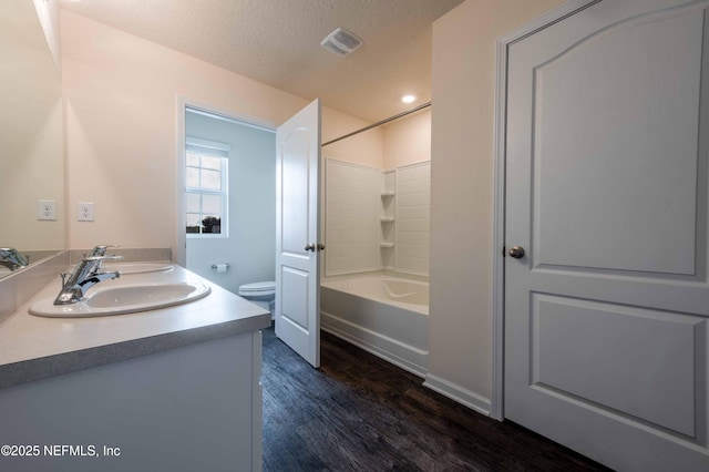 full bathroom featuring washtub / shower combination, toilet, a textured ceiling, vanity, and hardwood / wood-style flooring