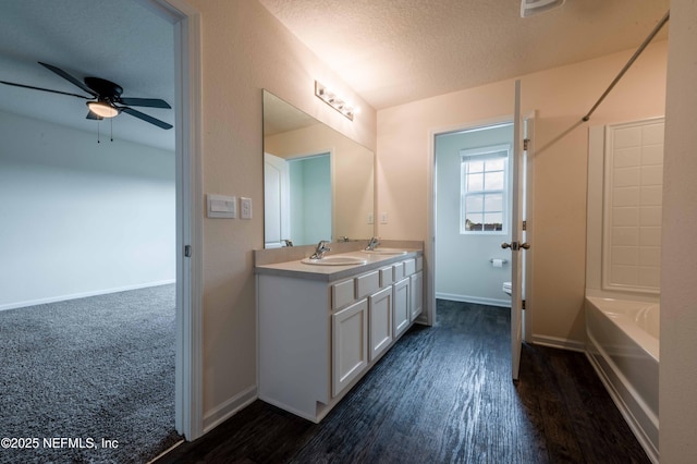 bathroom with hardwood / wood-style flooring, ceiling fan, vanity, a textured ceiling, and toilet