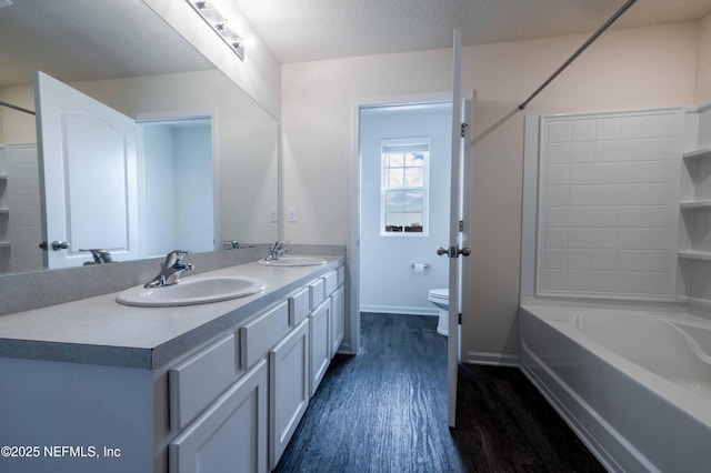 full bathroom with hardwood / wood-style flooring,  shower combination, vanity, a textured ceiling, and toilet