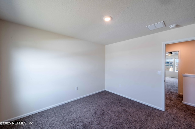 empty room with dark carpet and a textured ceiling