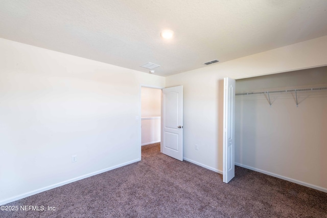 unfurnished bedroom with a closet and dark colored carpet