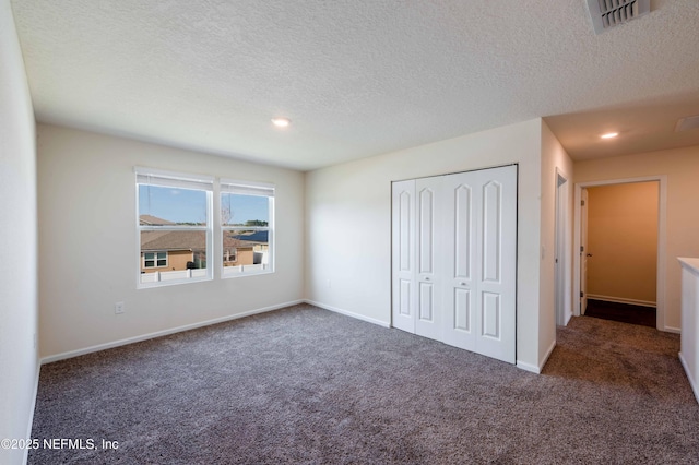 unfurnished bedroom featuring a closet, dark carpet, and a textured ceiling