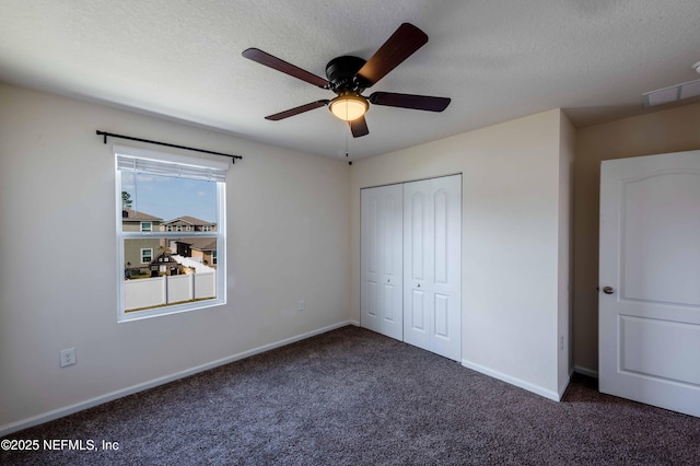 unfurnished bedroom featuring ceiling fan, a closet, a textured ceiling, and dark colored carpet