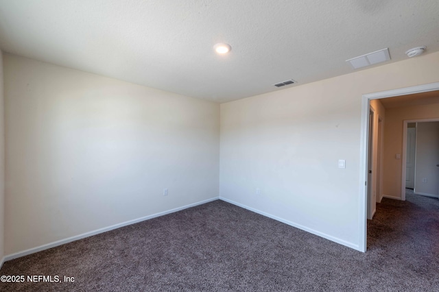 empty room with a textured ceiling and dark carpet