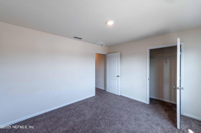 unfurnished bedroom featuring dark colored carpet, a textured ceiling, and a closet